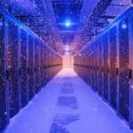 A hallway in a data center, lined with server rows, ends with a solitary blue light glowing atop one row